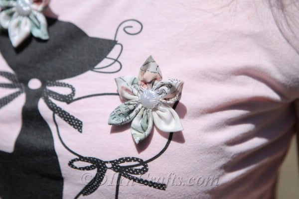 A fabric flower pinned to a t-shirt.