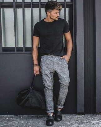Slip-on Sneakers Outfits For Men: Rock a black crew-neck t-shirt with grey chinos to put together a cool and casual outfit. The whole getup comes together wonderfully if you introduce a pair of slip-on sneakers to your ensemble.