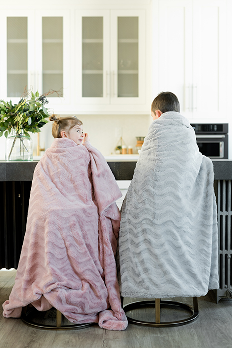 Two small children sitting in the kitchen wrapped in blankets 