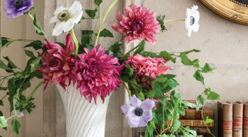 Loose, garden inspired arrangement of dark pink dahlias, white and light purple anemones, and trailing vines by floral designer Mieke ten Have in a white pottery vase
