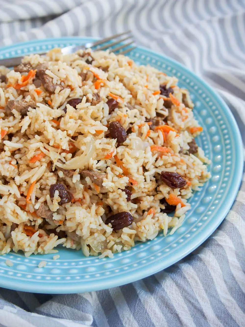plate of lamb pilaf with fork behind