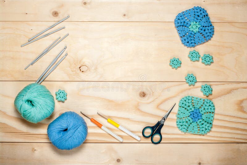 Accessories for knitting. Balls of yarn. Crocheted blue-and-green patterned cloth. Hooks and scissors on light wooden background. stock photography