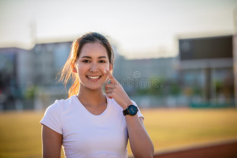 Asian Woman applying and spraying sunscreen cream on skin before run. Sports and healthy concept royalty free stock photography