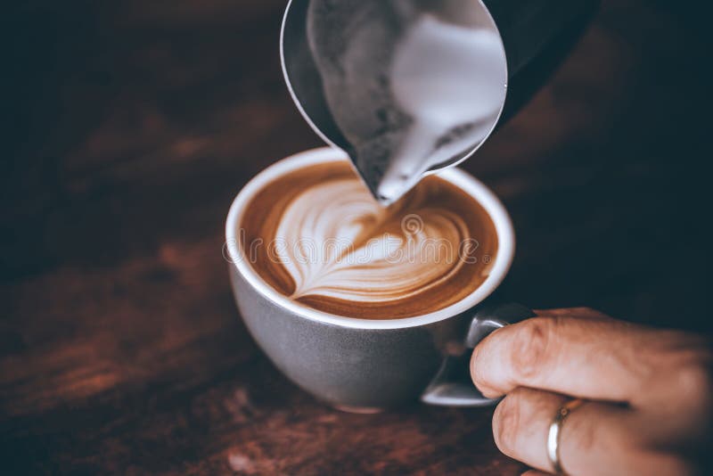 Barista making pouring stream milk with coffee latte art pattern heart shape.  stock photography