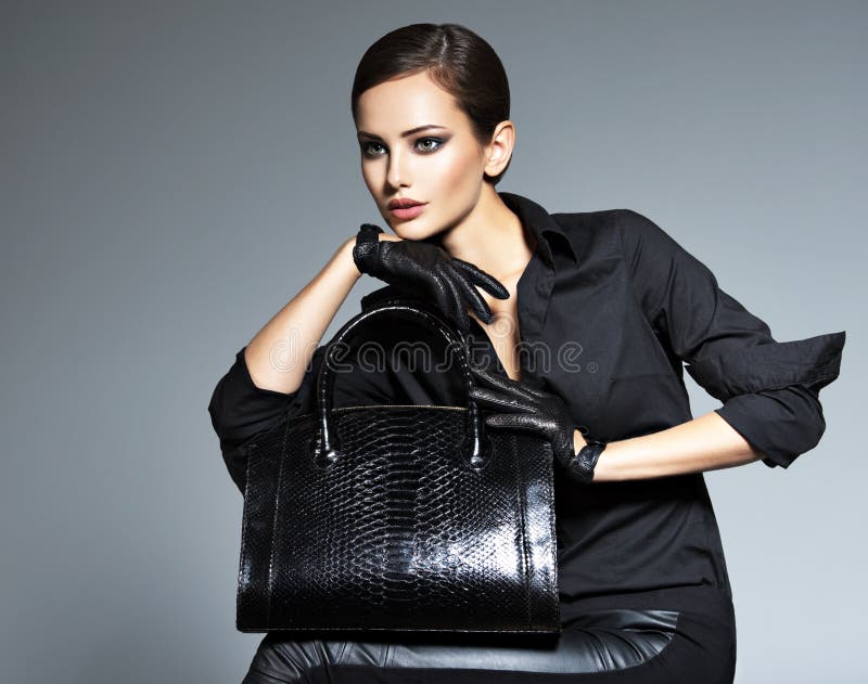 Beautiful woman in black  holds fashion handbag. Posing at studio royalty free stock photo