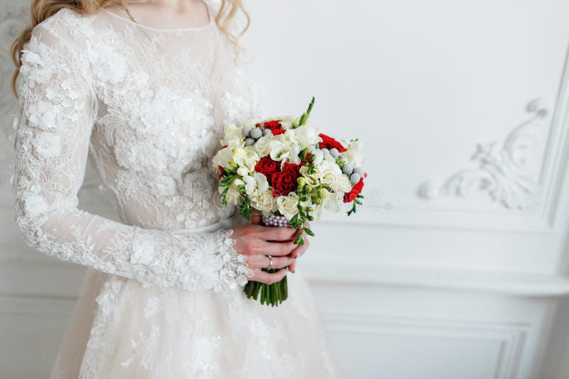 Bride holding bridal bouquet close up. red and white roses, freesia, brunia decorated in composition stock photos