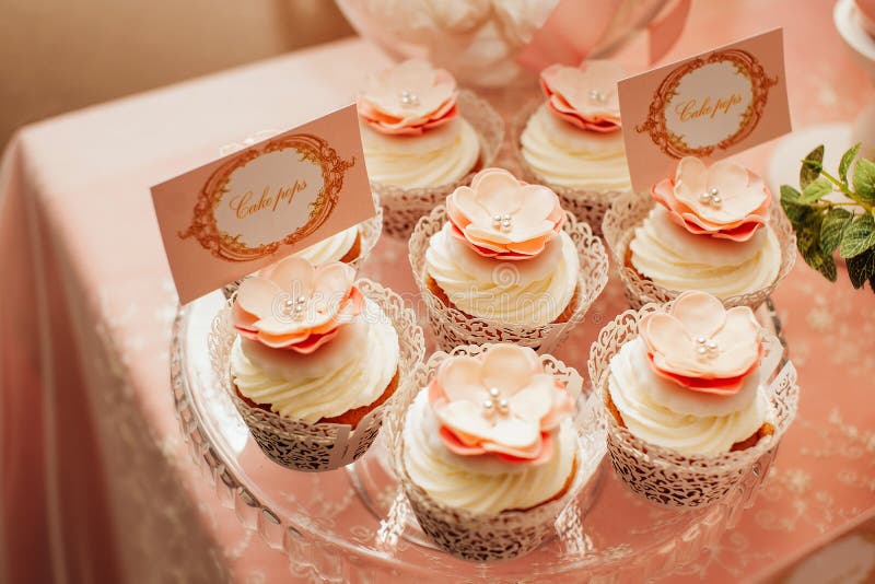 Cake POPs decorated with flowers and cream on a sweet peach-colored wedding table stock photography