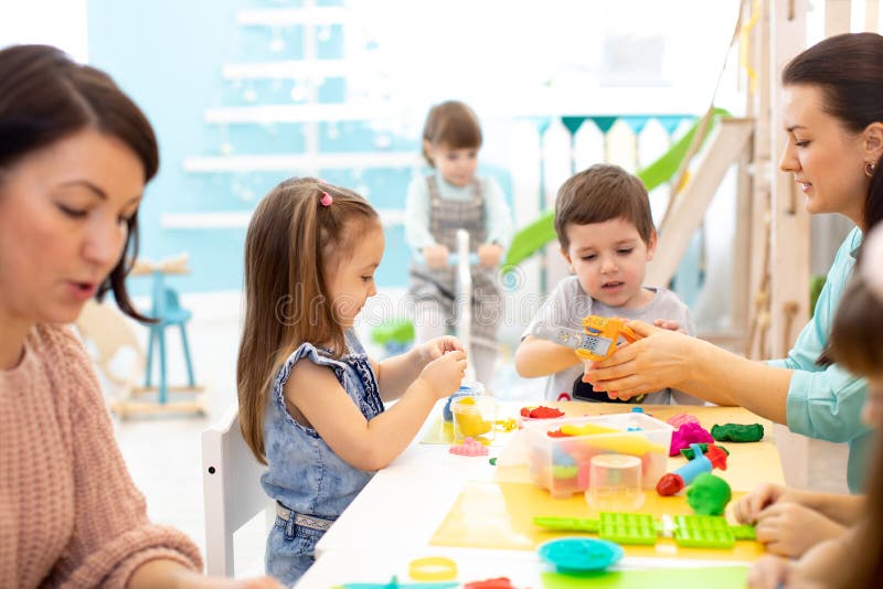 Children dough play in daycare centre. Kids mold from plasticine in kindergarten. Little students knead modeling clay with hands stock photo