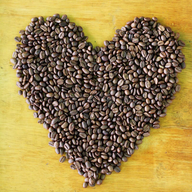 Coffee bean pattern. Heart pattern from coffee bean on wooden background stock images