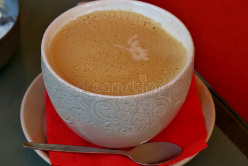 Coffee in a white cup with a pattern on a saucer with a red napkin. Close up royalty free stock photo