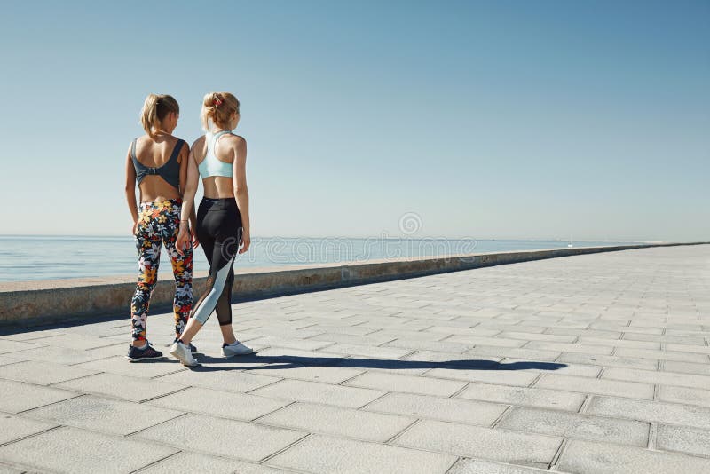 Couple female running exercising jogging happy on waterfront. Training as part of healthy lifestyle. Two back young fit girls runners royalty free stock photography