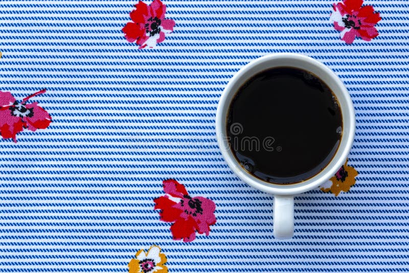 A Cup of Black Coffee on Cloth with Seamless Blue Horizontal Stripes and Colorful Flowers Pattern. Top view of a cup of black coffee on cloth with seamless blue royalty free stock photo