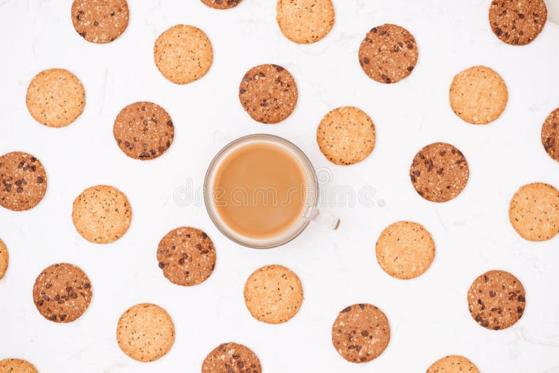 Cup of coffee among pattern of various shortbread and oat cookie. S with cereals and raisin on black wooden background. Top view, flat lay royalty free stock image