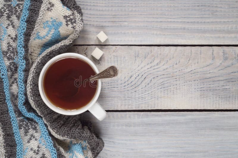 A cup of tea and a knitted scarf on the background of a white wo stock image