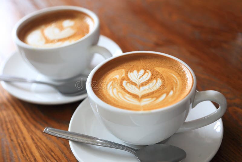 Two cups of coffee latte art with tulip pattern on wooden table with copy space. Cups of coffee latte art with tulip pattern on wooden table with copy space stock photography