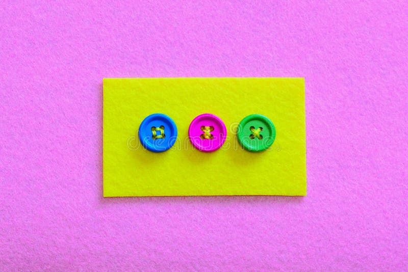 Easy ways to sew buttons to felt. Yellow felt piece with colourful buttons isolated on pink felt background royalty free stock photos