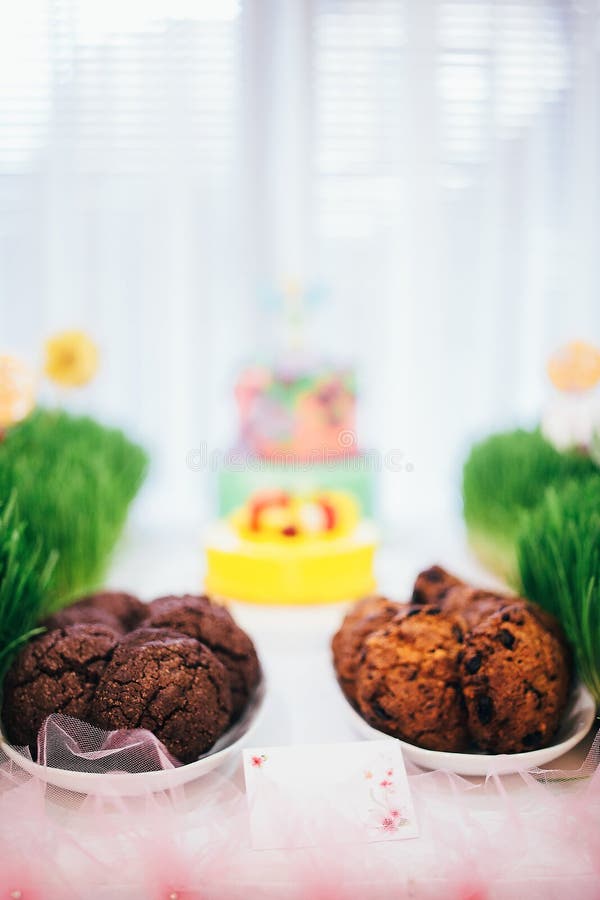 Festive table with a large cake with mastic flowers. Candy bar with grass on which a cake with cookies and lollipops.  stock image