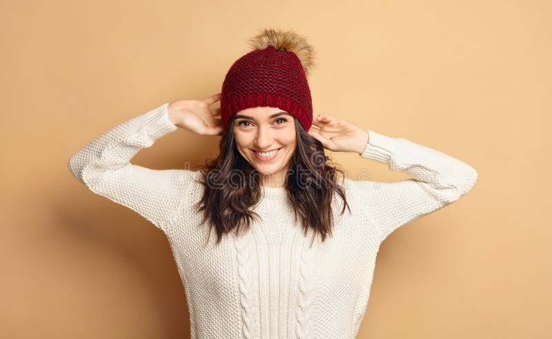 Girl in Knitted Sweater and Beanie Hat over beige background stock photos