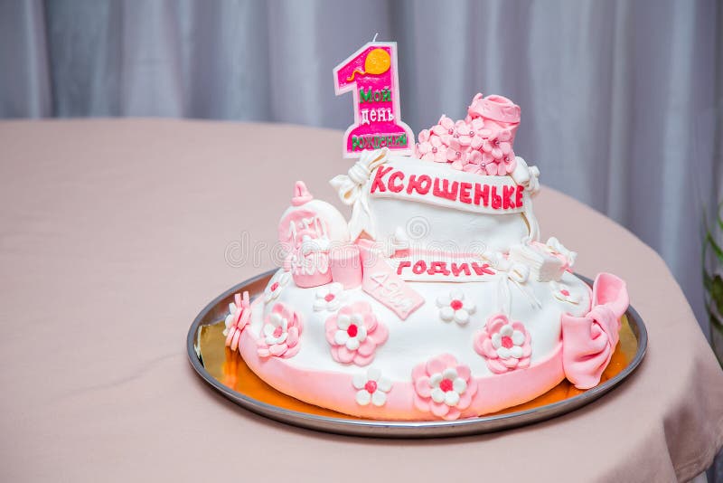 Girlish cake with pink mastic flowers and cnumber 1. One year old first birthday party. Inscription on candle My birthday. Inscription on cake - name Ksushenka royalty free stock images