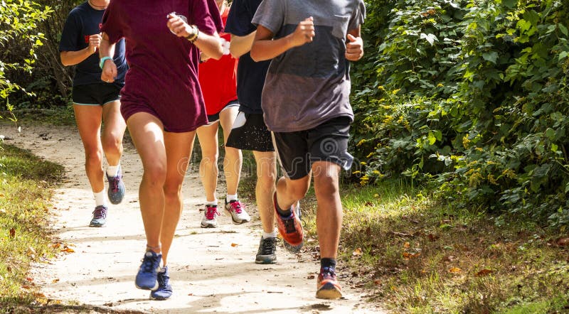 Group of runners on a dirt trail running. A group of high school runners are training together on a dirt path on a sunny afternoon, running toward the camera stock photos