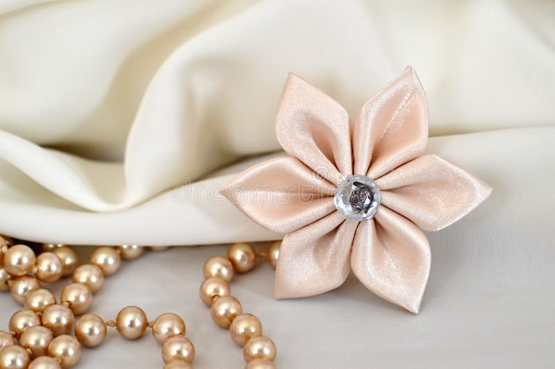 Handmade silk kanzashi flower and pearls. On fabric background royalty free stock photography