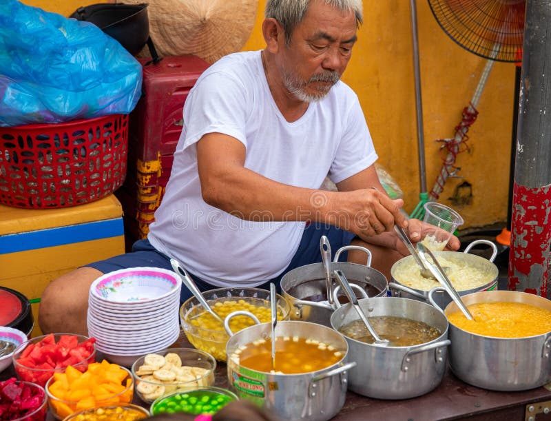 Hoi An, Vietnam - 28 Jul 2019: local eatery with food seller and soup bowl. Vietnamese street food. Old man cook soup stock photos