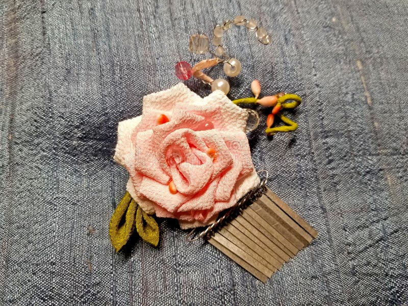 Kanzashi Comb with Handmade Fabric Flower -10. Japanese kanzashi hand made flower and comb constructed from kimono material on a gray fabric background royalty free stock images