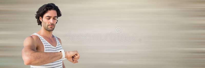 Man in training gear looking at watch against blurry cream background royalty free stock photography