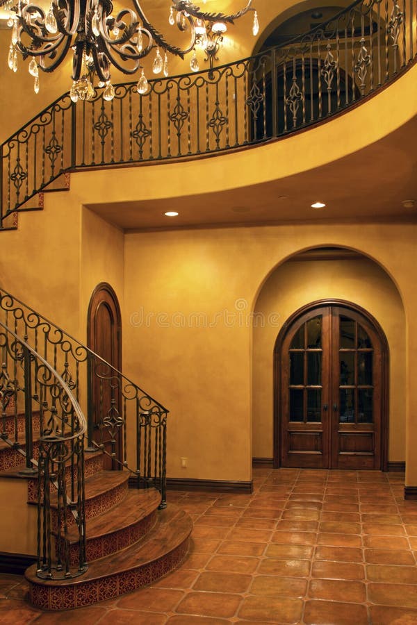 Mansion home interior front stairway entrance. Luxurious mansion home front entryway stairs with wrought iron railing royalty free stock image