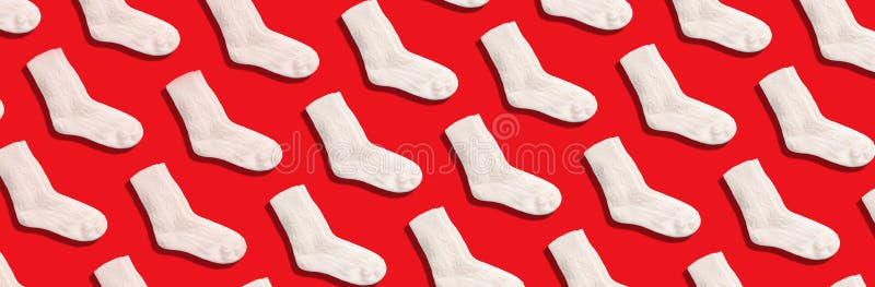 Pair of white woolen knitted socks pattern on red background. Top view. Copy space. Creative design for packaging. Christmas and stock photography