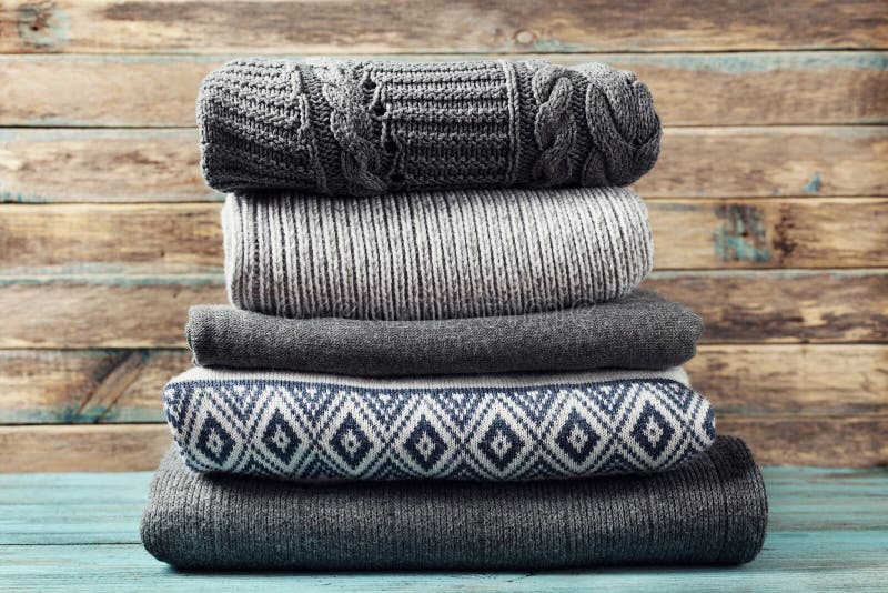 Pile of knitted winter clothes on wooden background, sweaters, knitwear stock photography