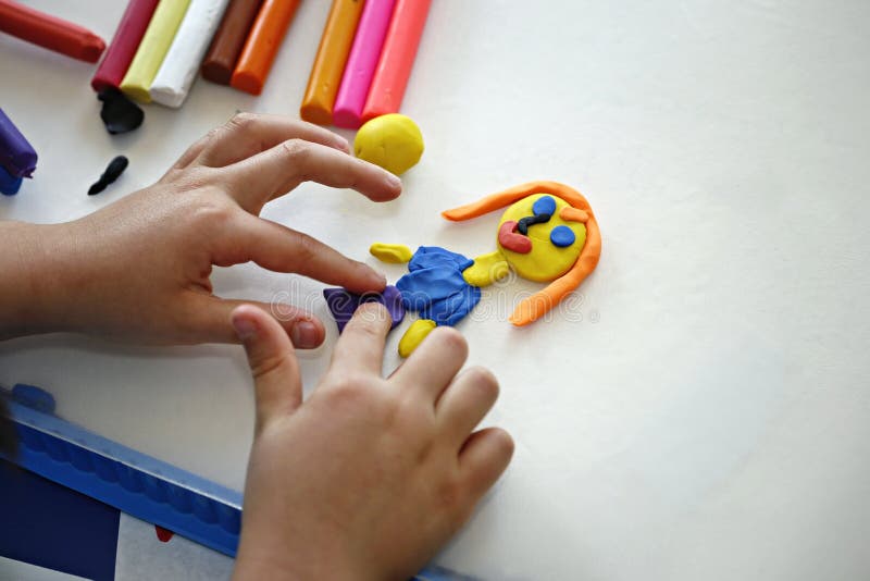 Plasticine. Hands of little girl making doll from colorful clay dough (plasticine stock photos