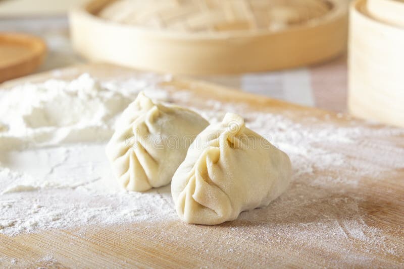 Raw manti, dumplings or wonton from dough with minced meat filling on the kitchen table with flour stock images