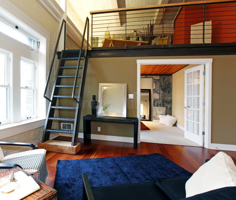 Reconstructed modern living room with mezzanine. View of modern reconstructed living room with mezzanine area above bedroom. View of iron steep stairs royalty free stock photography