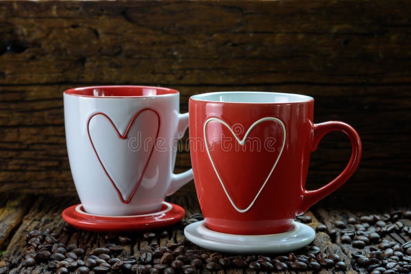 Romantic design of two coffee cups with heart shape pattern and coffee beans. On wooden background royalty free stock photos