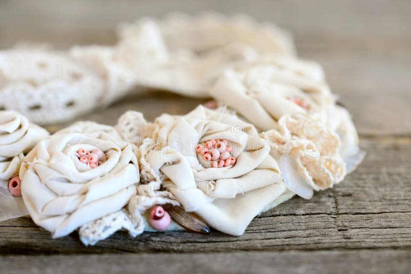 Romantic shabby chic necklace on a vintage wooden background. Beautiful flower necklace made of cotton fabric, lace ribbons. Fabric art. Fabric roses. Boho chic stock photo