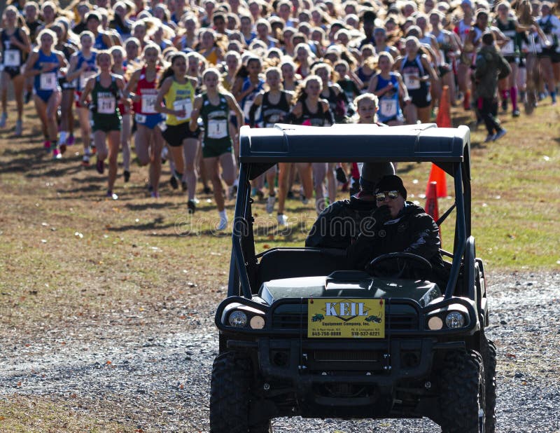 Runners following cart at the start of a girls cross country race. Wappingers Falls, New York, USA - 23 November 2019: High school girls cross country runners stock image