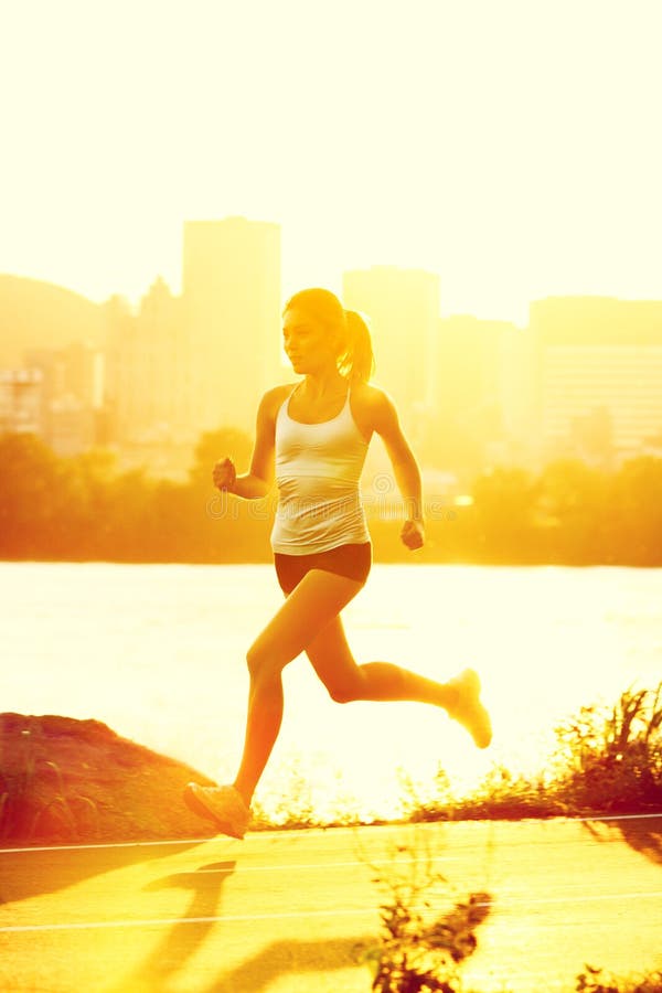 Runners - woman running. Outdoors in sunshine. Young woman jogging in city of Montreal, Quebec, Canada stock images
