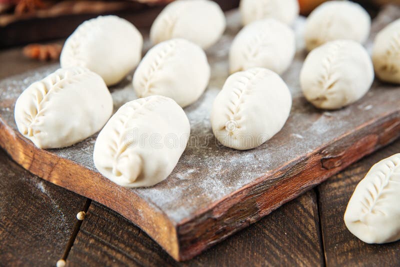 Semi-finished manti dumplings on the wooden board royalty free stock image