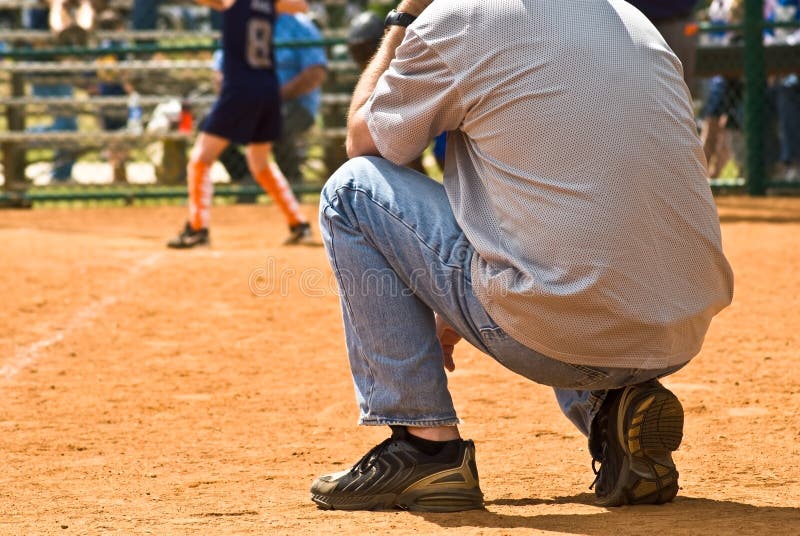 Sideline Coach/Girls Softball. A man on the sidelines at a girls softball game watching the batter and ready to tell the runners what to do stock photos