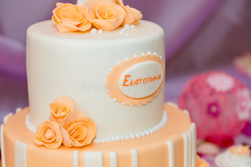 Soft focused shot of white birthday cake for girl with orange mastic rose flowers. Inscription in Russian - Ekaterina stock photo