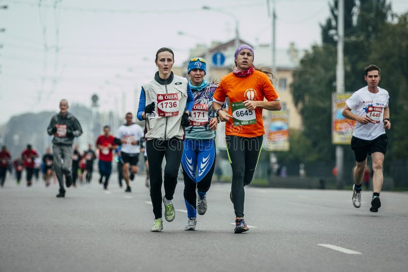 Three girls runners run through streets of city. Omsk, Russia - September 20, 2015: three girls runners run through streets of city during Siberian international stock photography