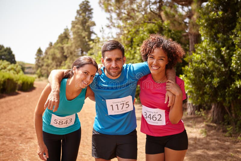 Three happy runners completed the race. Three happy runners at the end of a cross country marathon with trees behind them wearing casual running clothes in the royalty free stock photography