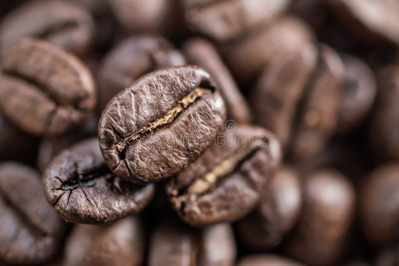 Three roasted coffee beans close up. Blurred coffee bean background. Top view.  royalty free stock image