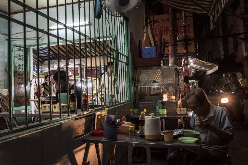 Vietnamese senior man is eating a noodle soup at a restaurant in a street of Ho Chi Minh City, Vietnam stock images