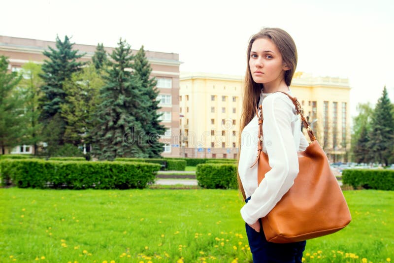 Woman with handbag. Outdoor portrait of young beautiful happy sensual woman with handbag, casual style, walking in city park royalty free stock photography