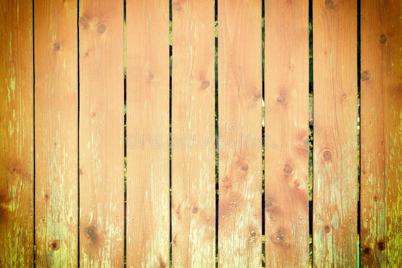 Wooden fence made of smooth orange boards. Texture of a wooden surface. Blank background, photo with vignette. royalty free stock photo