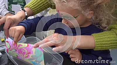 Excited daughter girl with mother make ebru painting on water. Gimbal motion stock video