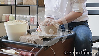 Woman working on potters wheel making dishes with their own hands. Close-up photo of dirty hands molding clay stock footage