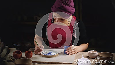 Woman Potter paints a plate made with his own hands. Manual work. Folk art stock video
